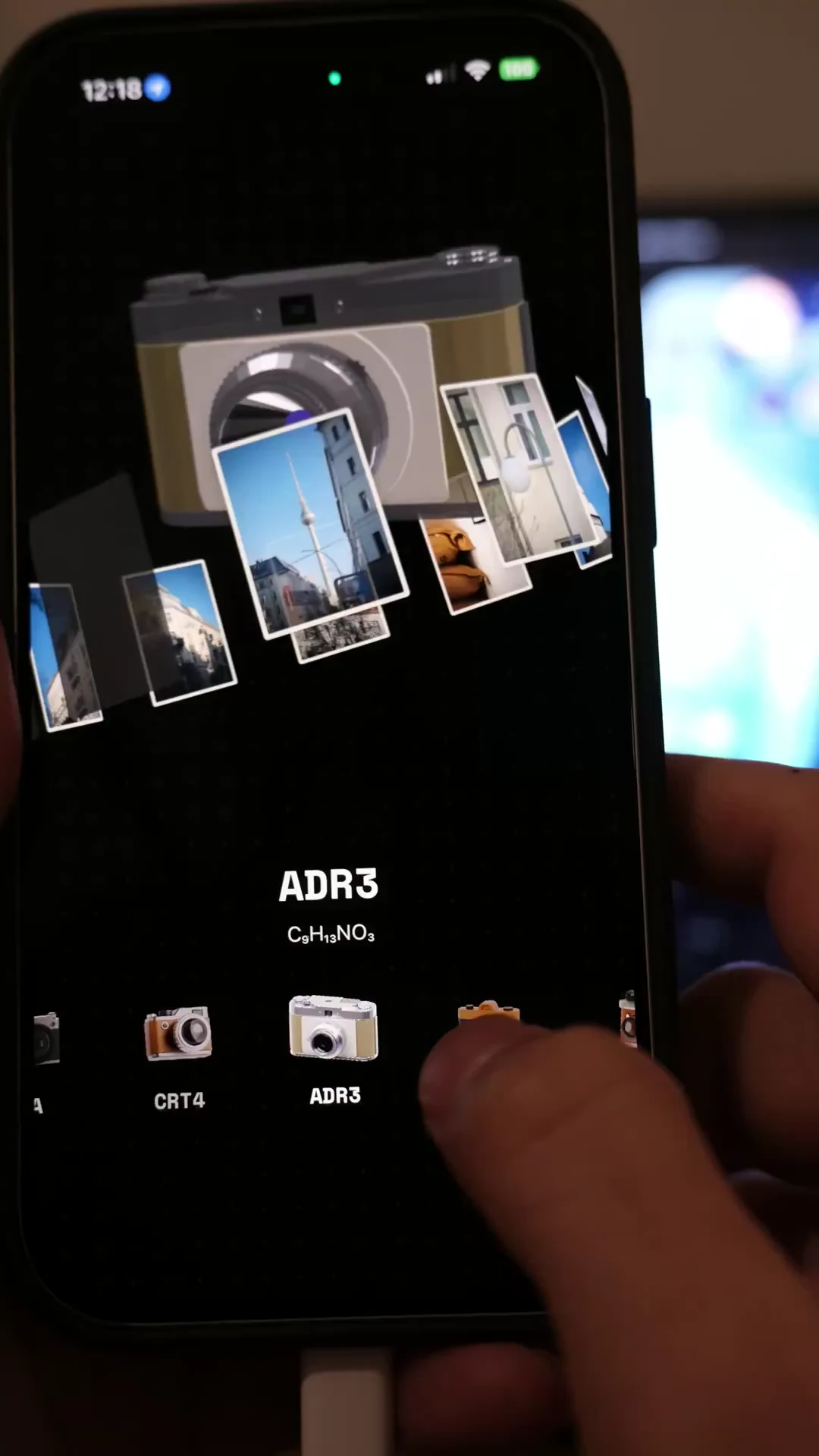 A physical iPhone showing Binsoo's interactive camera models and floating photo previews